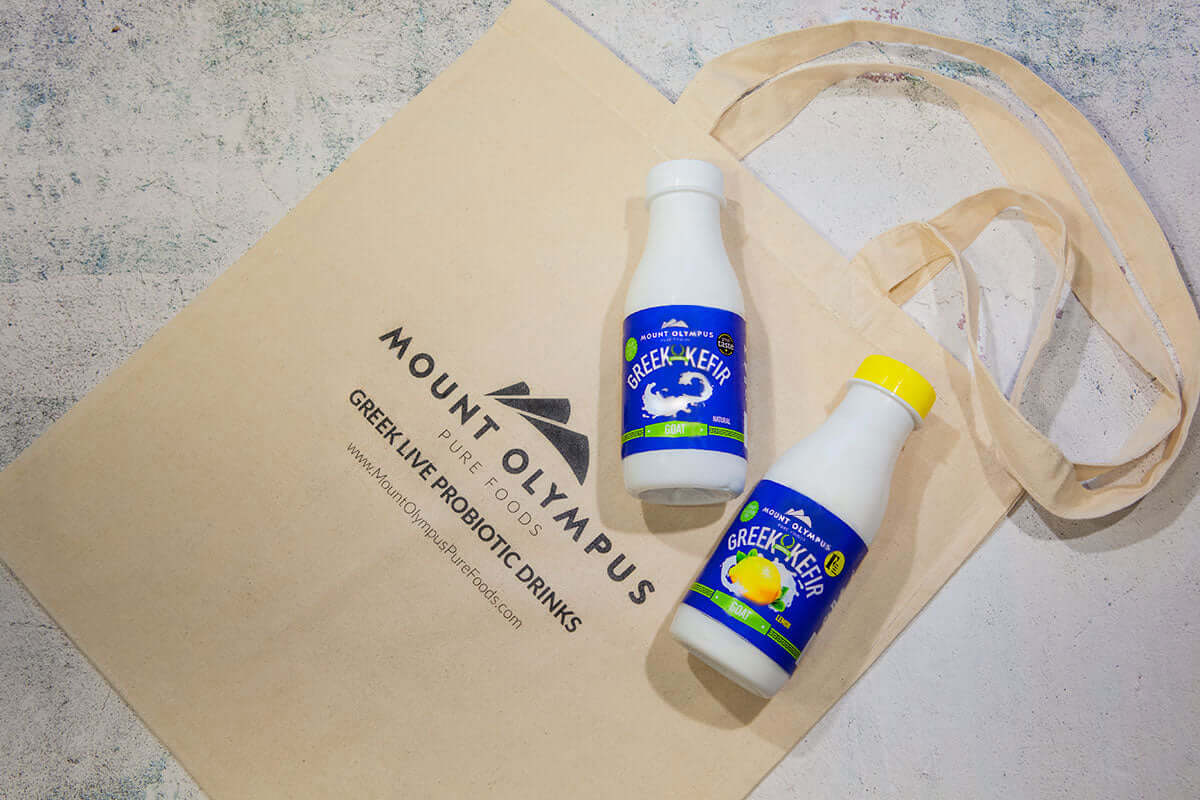Greek Kefir bottles in a tote bag showcasing Mount Olympus branding, highlighting a healthy probiotic drink.